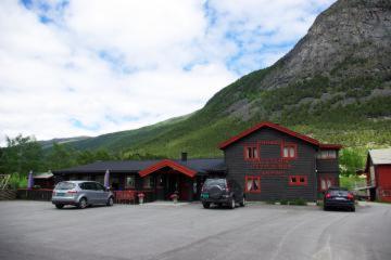 un edificio con auto parcheggiate di fronte a una montagna di Mogard a Skjåk