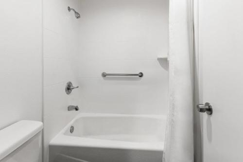a white bathroom with a tub and a shower at Days Inn by Wyndham Arroyo Grande Pismo Beach in Arroyo Grande