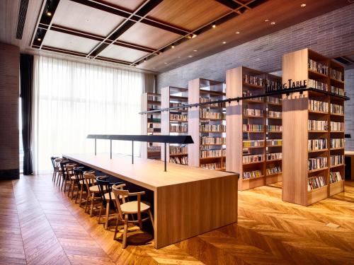 a library with a long table and chairs in it at IN THE LIBRARY hotel and books TOKOROZAWA - Opening in 15th July 2025 in Tokorozawa