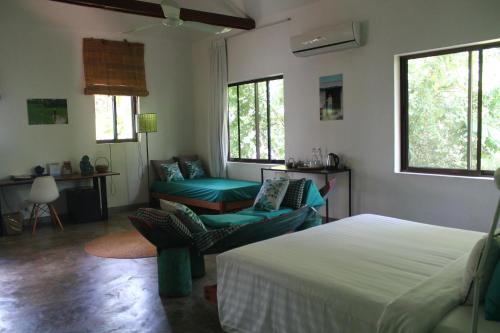 a bedroom with a bed and a couch and windows at Sala Baï Hotel & Restaurant School in Siem Reap