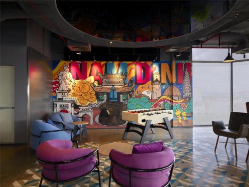 a room with purple chairs and a wall with a mural at Tru by Hilton Nam Dinh City Centre in Nam Ðịnh