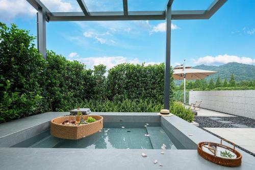 a patio with a pool of water with two baskets and an umbrella at Z HOTEL- Qingchengshan in Dujiangyan