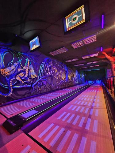 a bowling alley with purple lanes and a wall with graffiti at Hotel Kasztel in Rzezawa