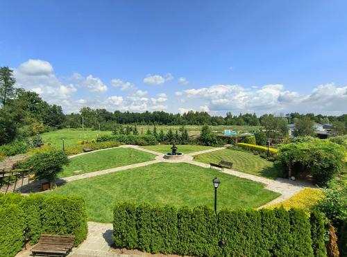 a park with a large lawn with a fountain at Hotel Kasztel in Rzezawa