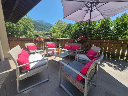 a patio with chairs and a table with an umbrella at Chalet avec Jacuzzi, billard, jardin clos, proche Paradiski in Aime La Plagne