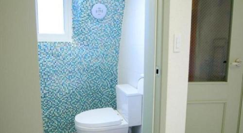 a bathroom with a toilet and a blue tiled wall at All That Water Pension in Gapyeong