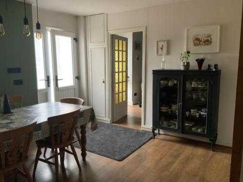 a dining room with a table and a china cabinet at Welcoming and peaceful bed and breakfast in Fougerolles-du-Plessis