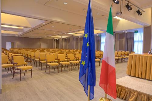 two flags in a room with chairs and tables at Hotel Federico II in Iesi