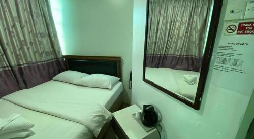 a small room with two beds and a mirror at Meriton Hotel in Singapore