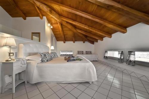 Schlafzimmer mit einem großen weißen Bett und Holzdecken in der Unterkunft Palazzo Dogana Rooms in Agropoli