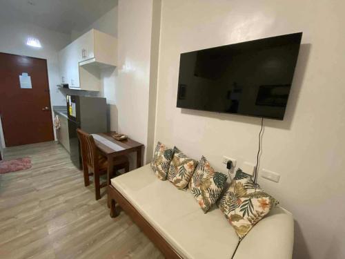 a living room with a couch and a television on a wall at Isabela III, Mesavirre Garden Residences in Bacolod