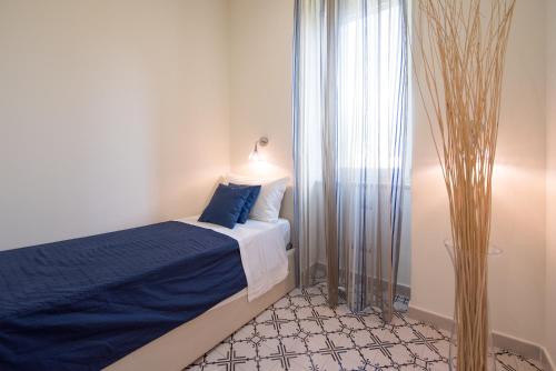 a bedroom with a bed with blue sheets and a window at Ravello House in Ravello
