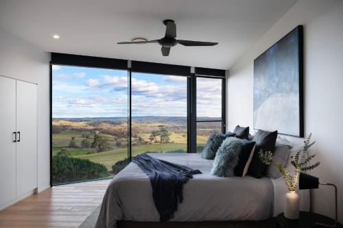 a bedroom with a bed with a large window at Sky High- iconic ridge-top retreat in Hepburn Springs
