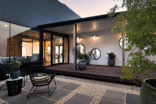 a house with a wooden deck with a chair and mirrors at Sky High- iconic ridge-top retreat in Hepburn Springs