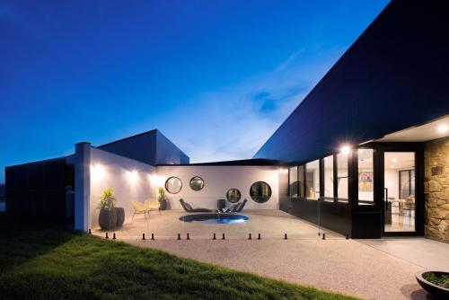 a large black house with a courtyard at night at Sky High- iconic ridge-top retreat in Hepburn Springs