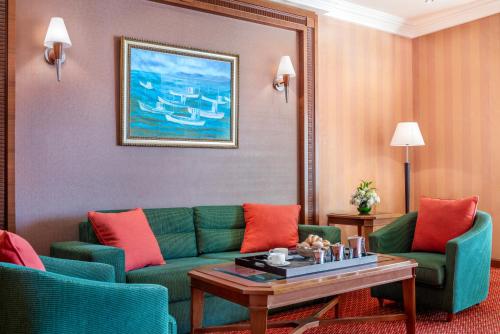 a living room with a green couch and two chairs at Al Raha Beach Resort & Spa in Abu Dhabi