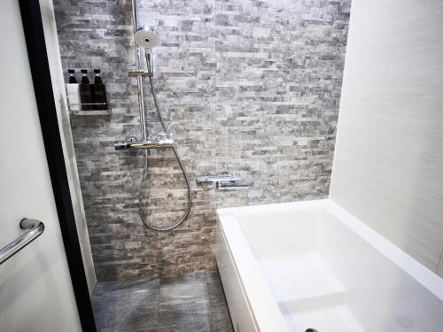 a bathroom with a shower with a brick wall at IN THE LIBRARY hotel and books TOKOROZAWA - Opening in 15th July 2025 in Tokorozawa
