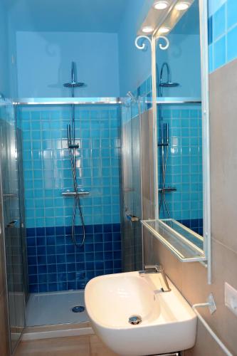a blue tiled bathroom with a sink and a shower at Alghero Sunrise in Alghero