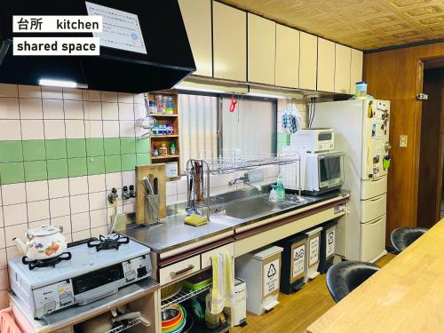 a kitchen with a sink and a microwave at TAKIO 5 guesthouse in Higashi-osaka