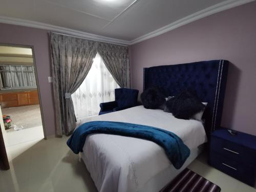 a bedroom with a bed with a blue headboard and a window at Blackpony Guesthouse in Kriel