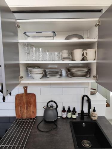 a kitchen with a sink and some dishes on shelves at PaprikanTiny House in Uppsala