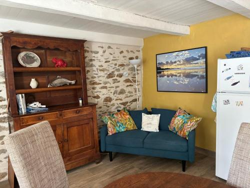 a living room with a blue couch and a shelf at L'air du large - Maison à 15min à pied de la plage in Le Palais