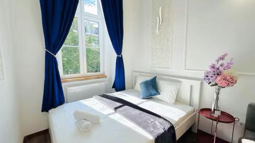 ein Schlafzimmer mit einem Bett mit blauen Vorhängen und einer Vase aus Blumen in der Unterkunft Apartment in Jozsef krt 50 in Budapest