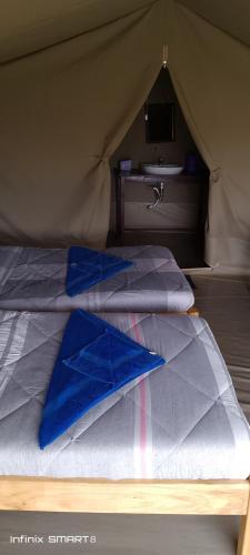 a bed in a tent with blue sheets and a sink at Enchoro mara in Sekenani