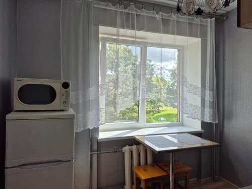 a kitchen with a window with a microwave and a table at Sunrise in Rēzekne