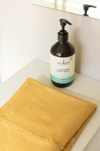 a bottle of soap sitting on a counter next to a sponge at Lake Illawarra Family Escape in Lake Illawarra