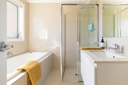 a bathroom with a tub and a sink and a shower at Lake Illawarra Family Escape in Lake Illawarra