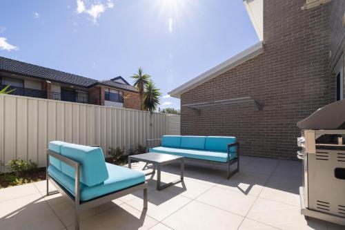 two blue chairs and a table on a patio at Lake Illawarra Family Escape in Lake Illawarra