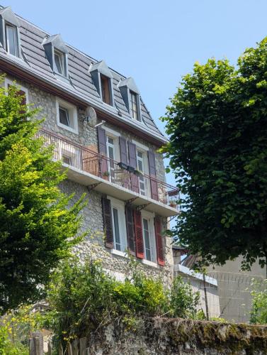 an old stone house with a balcony and trees at La Chartr’heureuse in the heart of the Park in Saint-Pierre-de-Chartreuse