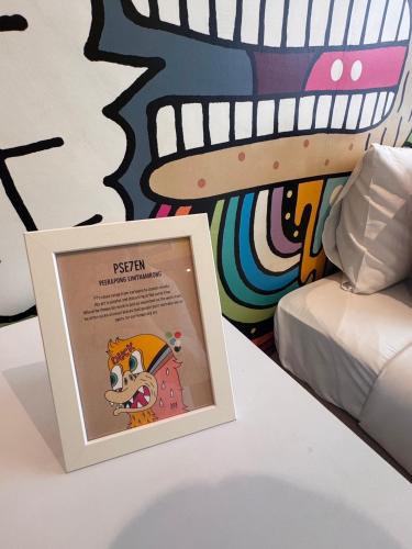 a picture frame on a table next to a mural at Beat Hotel Bangkok in Bangkok