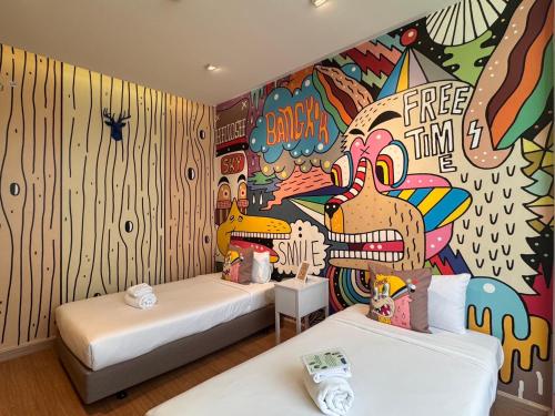 two beds in a room with a mural on the wall at Beat Hotel Bangkok in Bangkok