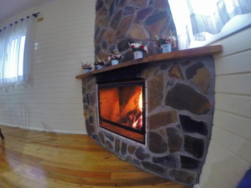 a stone fireplace with a fire in a room at Pousada Cabanas Xokleng in Urubici
