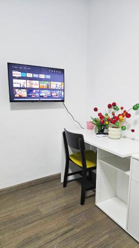 a white desk with a chair and a monitor on a wall at Downtown Rooms, 200m from Marina Beach in Larnaka