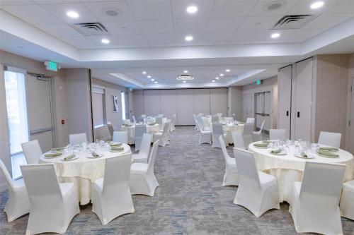 a banquet hall with white tables and white chairs at Hilton Garden Inn Lakewood in Lakewood