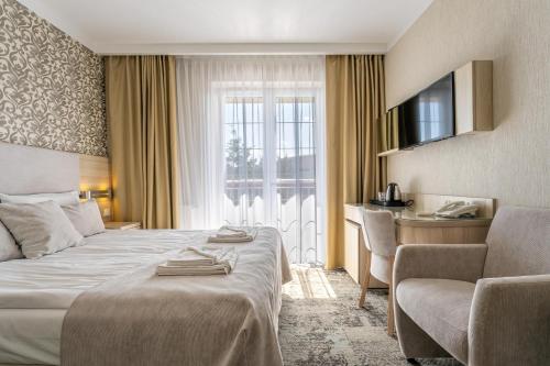 a hotel room with a bed and a chair and a window at Villa Cannes Jastarnia in Jastarnia