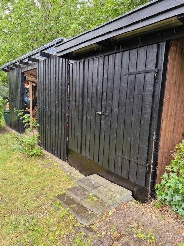 a black garage with a door in a yard at Quiet Area, 15 Km To The Beach in Skibby