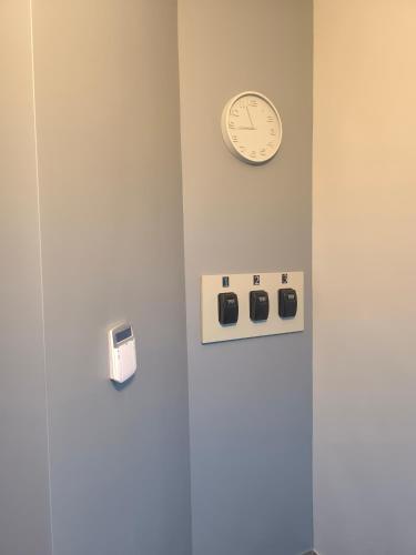 a clock on a wall next to a wall with switches at Apartamentai1 in Utena