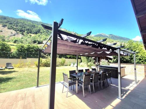 a patio with a table and chairs under a canopy at Chalet avec Jacuzzi, billard, jardin clos, proche Paradiski in Aime La Plagne