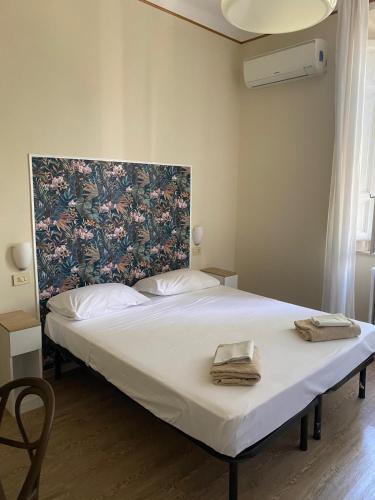 a bedroom with a large white bed with a floral headboard at Hotel Stipino in Lucca