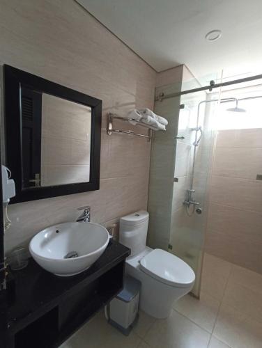 a bathroom with a sink and a toilet and a mirror at Orchids Ocean Hotel in Da Nang