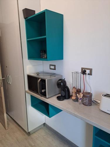 a kitchen counter with a microwave and a blue cabinet at Alezzi Seaside in Năvodari