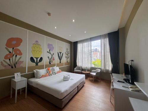 a bedroom with a bed and a desk and a television at Beat Hotel Bangkok in Bangkok
