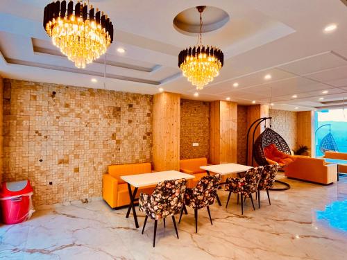 a restaurant with tables and chairs and chandeliers at Hotel Classic Crown - #scenic mountain view #open terrace #parking #premium rooms with balcony #guest preferred #best selling hotel in mussoorie in Mussoorie