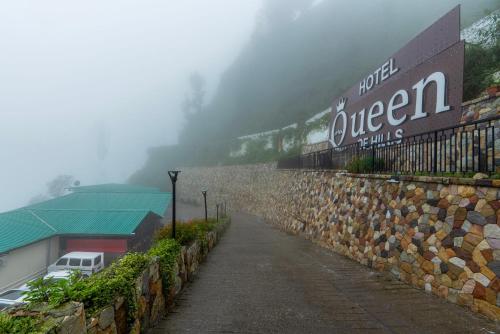 a sign on a stone wall next to a building at Treebo Premium Queen Of Hills Near Mall Road in Mussoorie