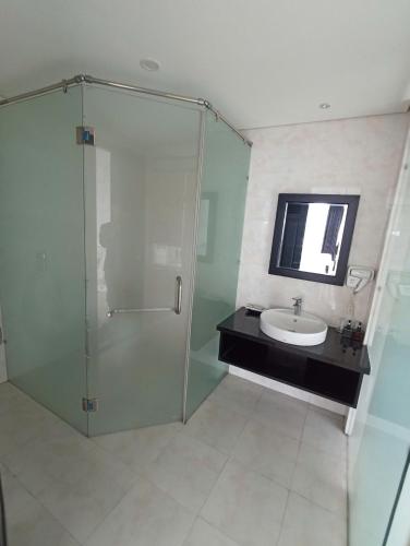 a bathroom with a glass shower and a sink at Orchids Ocean Hotel in Da Nang