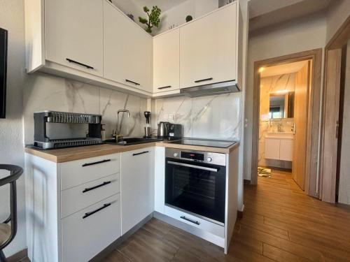 a kitchen with white cabinets and a stove top oven at Chloe Stay Complex by Horizon Homes in Orfánion